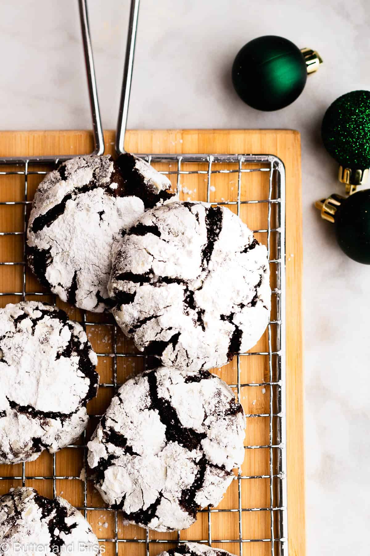 Chocolate crinkle cookies with striking white powdered sugar on a wire rack.