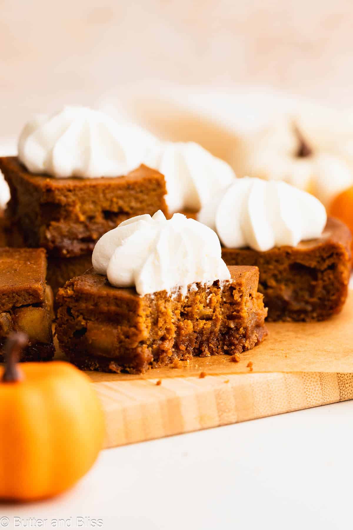 Bite revealing the layers in a gluten free pumpkin apple pie bar with whipped topping.