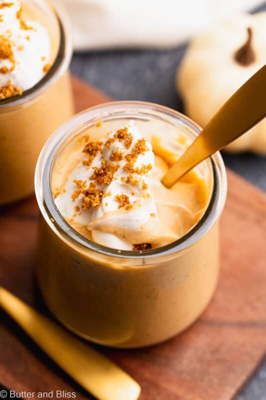 A creamy swirl of pumpkin pudding topped with whipped cream in a small serving glass.