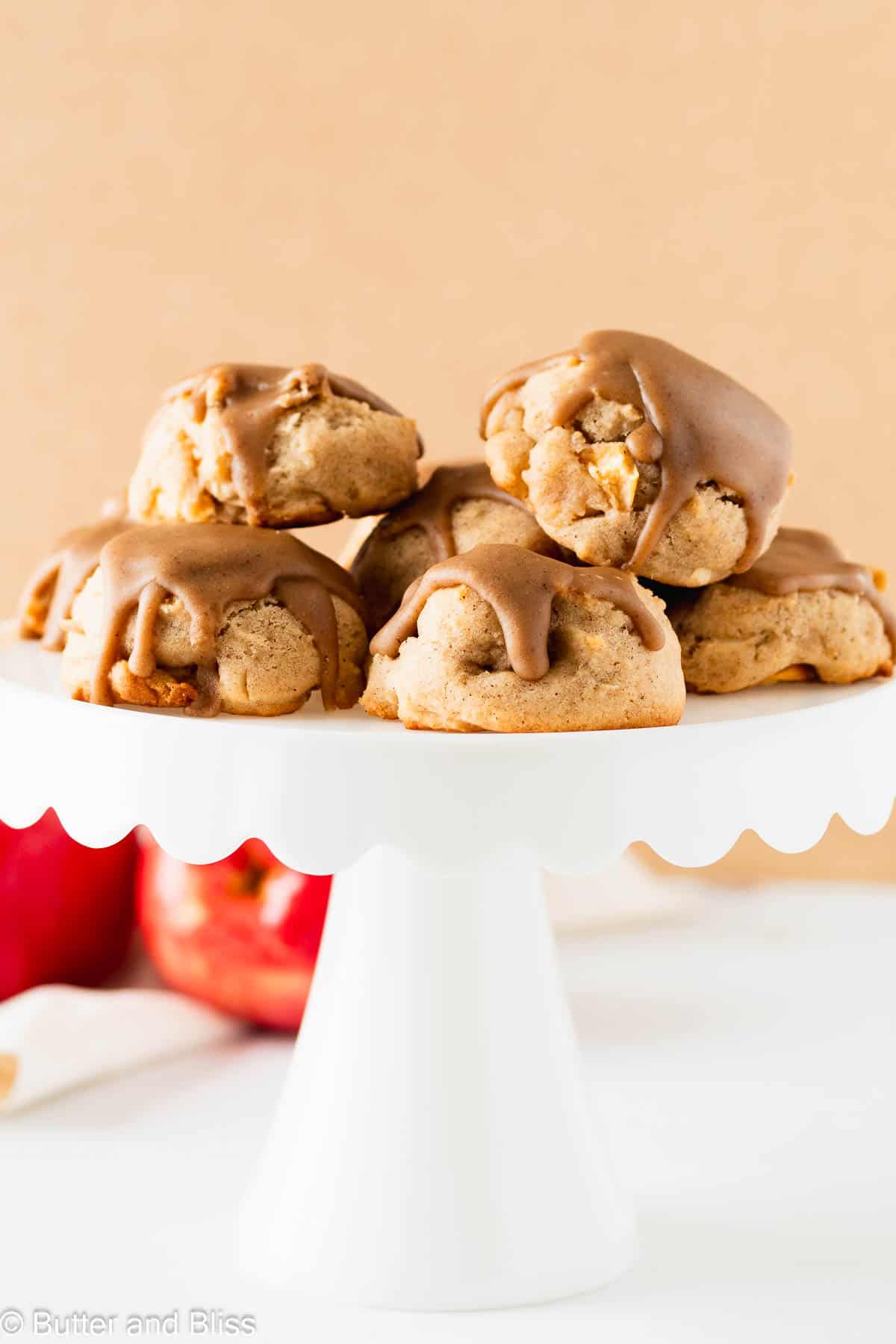 A cake stand full of soft caramel iced apple cookies.