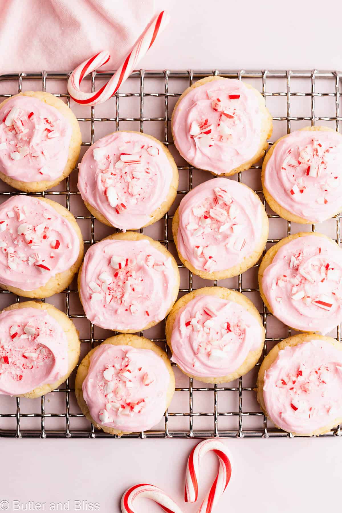 A wire rack full of pretty pink Christmas cookies topped with crushed candy canes.
