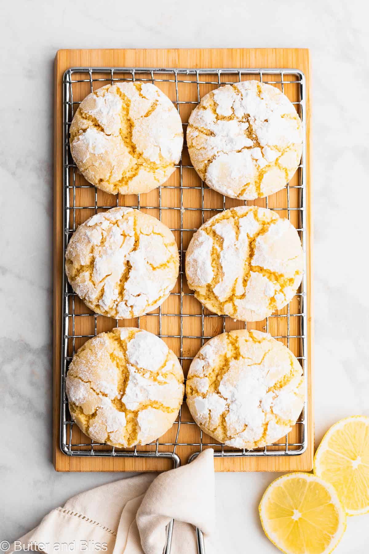 Fresh baked gluten free lemon crinkle cookies cooling on a wire rack.