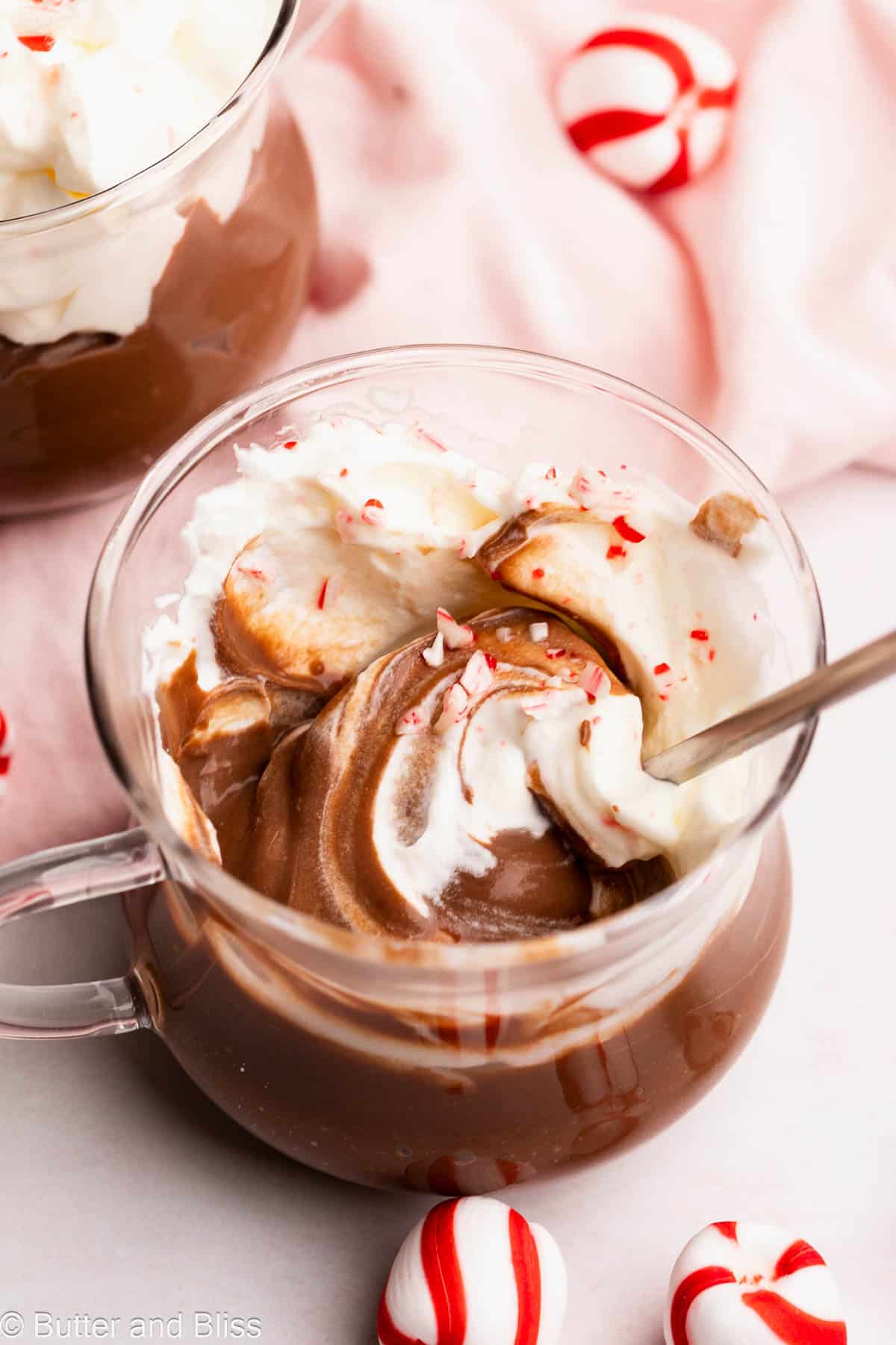 Super creamy holiday pudding in a glass mug surrounded by candy canes candies.