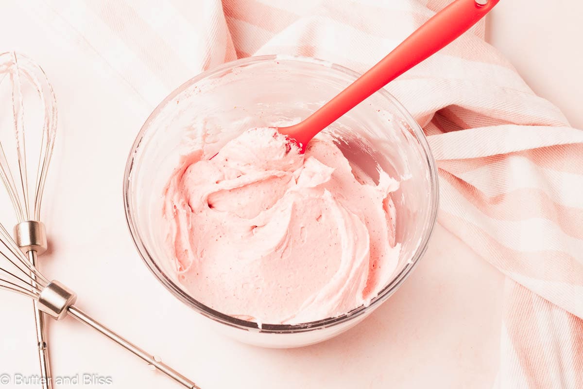 A glass bowl full of fluffy strawberry whipped cream.