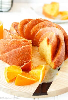 Beautiful whole orange butter cake made in a bundt pan on a wood tray.