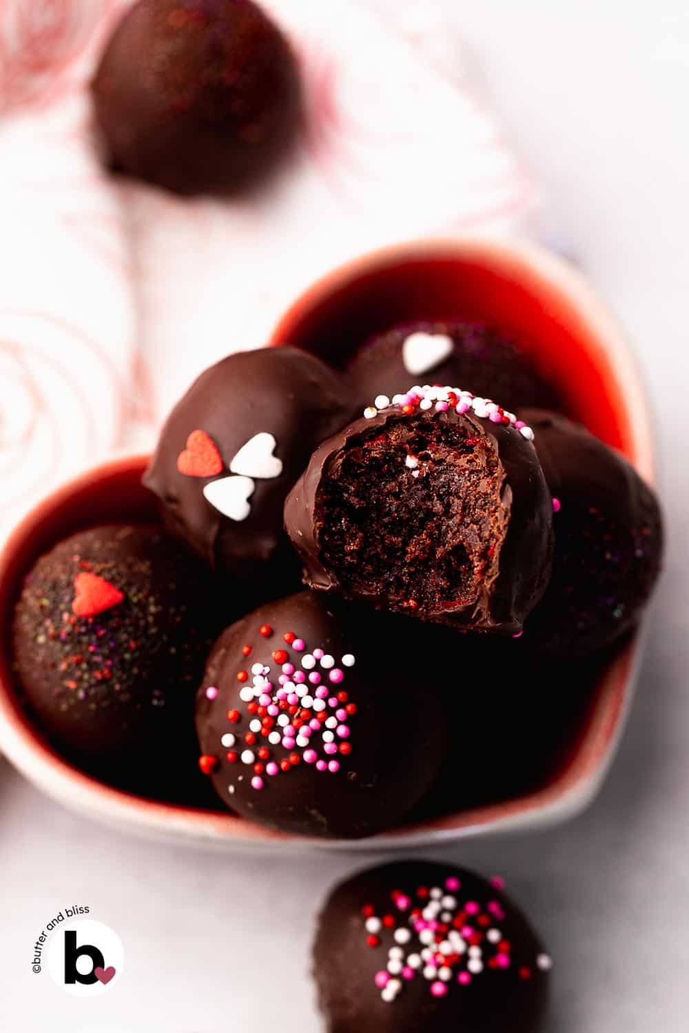Chocolate covered cake truffles with Valentine's sprinkles in a heart bowl.