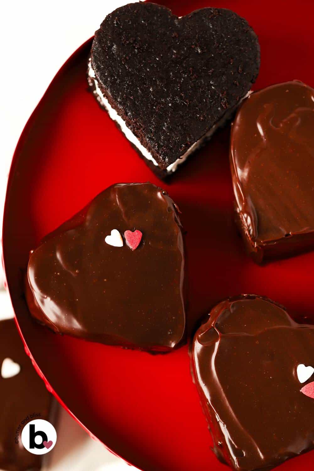 Mini heart shaped chocolate cakes on a red cake platter.