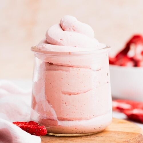 Swirls of strawberry whipped cream piped into a small jar.