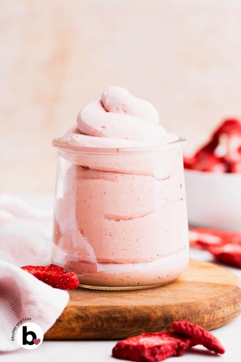 Swirls of strawberry whipped cream piped into a small jar.