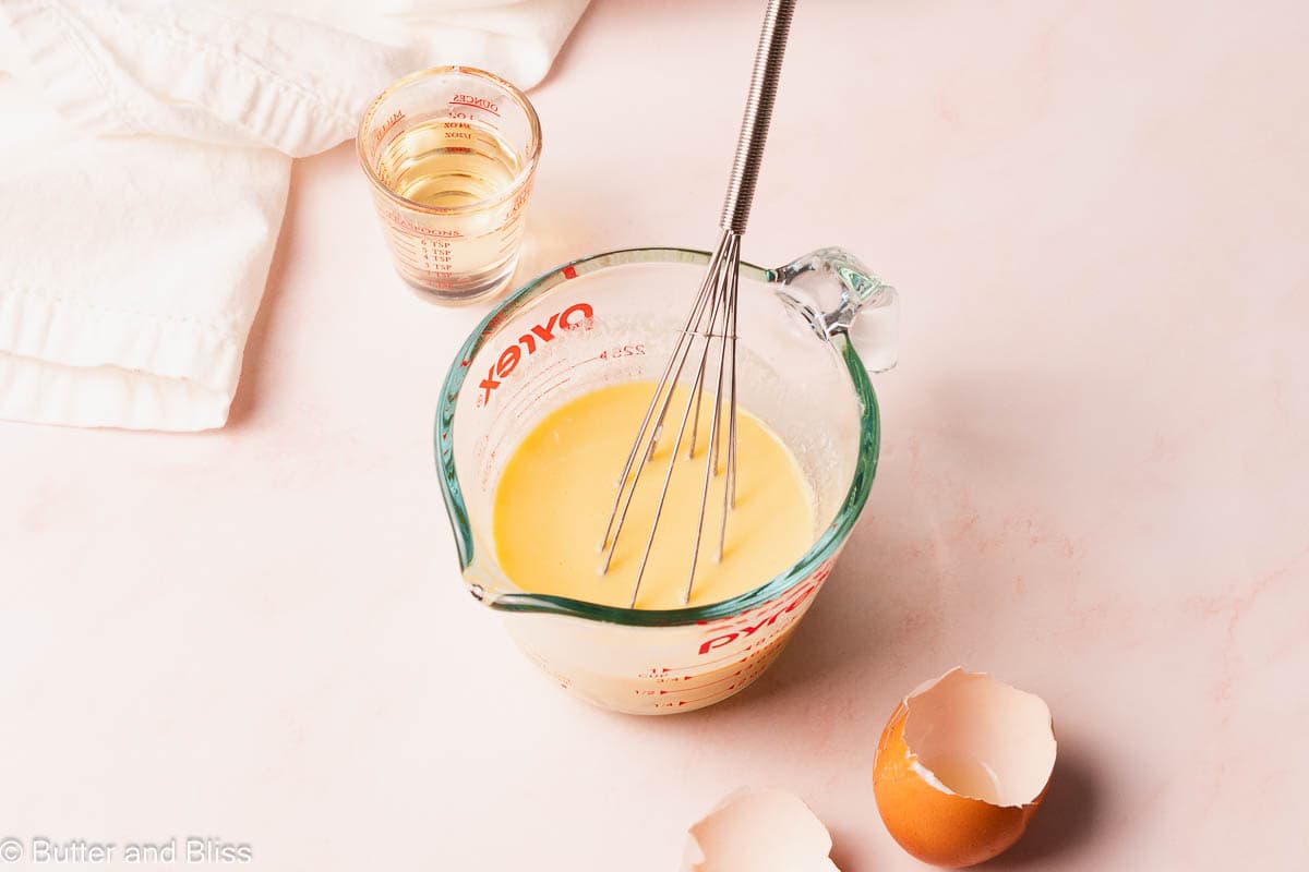 Egg, buttermilk, and oil mixed together in a liquid measuring cup.