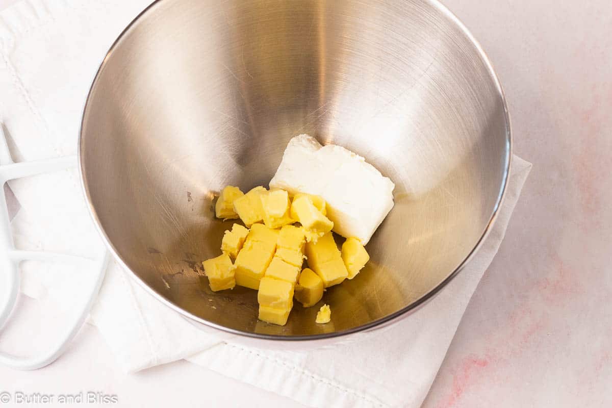 Cream cheese and butter in a silver mixing bowl.