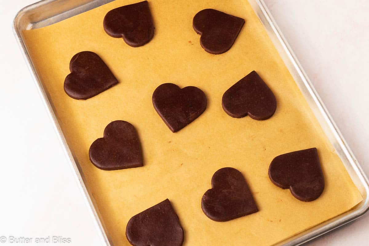 Heart shaped chocolate cut out cookies on a baking sheet.