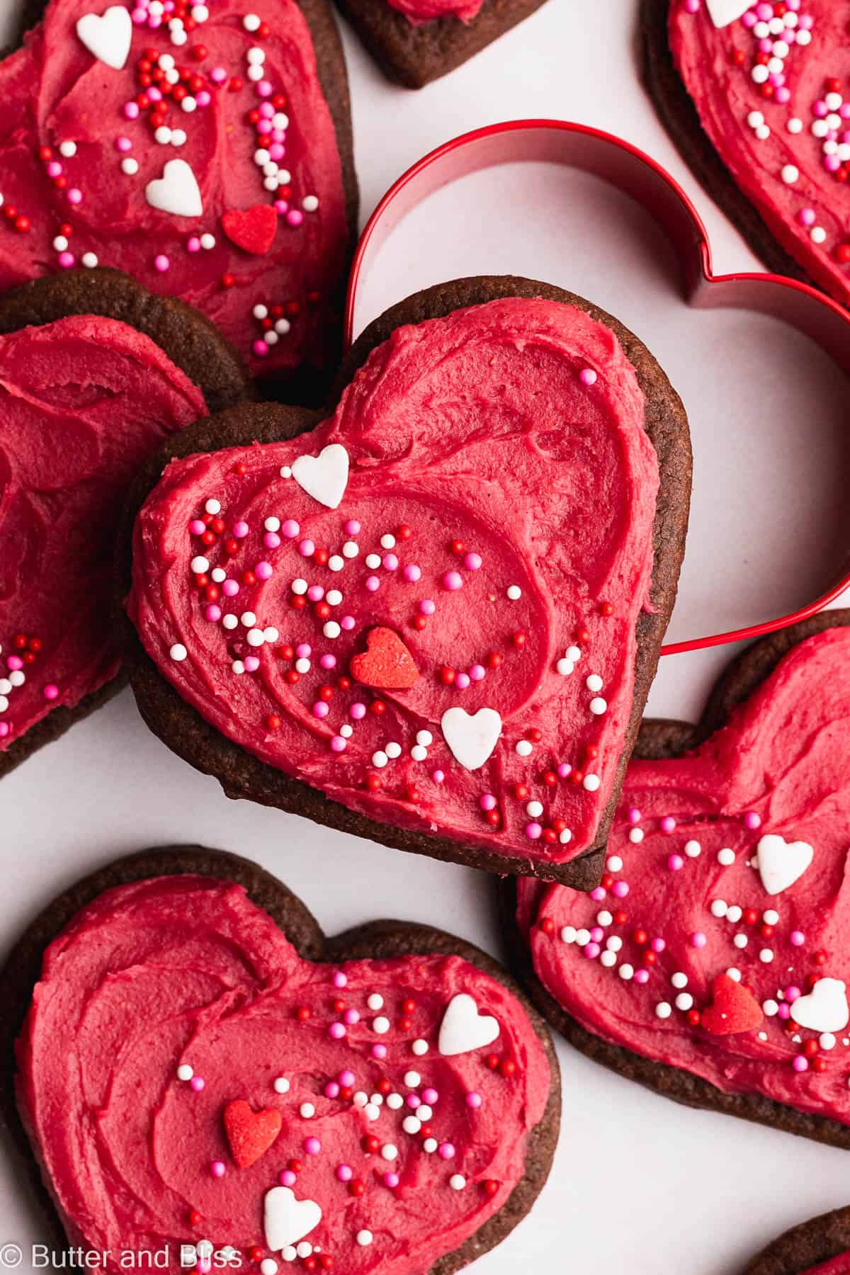 Close up of soft heart shaped chocolate cookies with bright pink frosting.