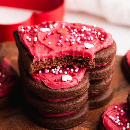 Chocolate heart shaped cookies in a stack with a tasty bite out of the top one.