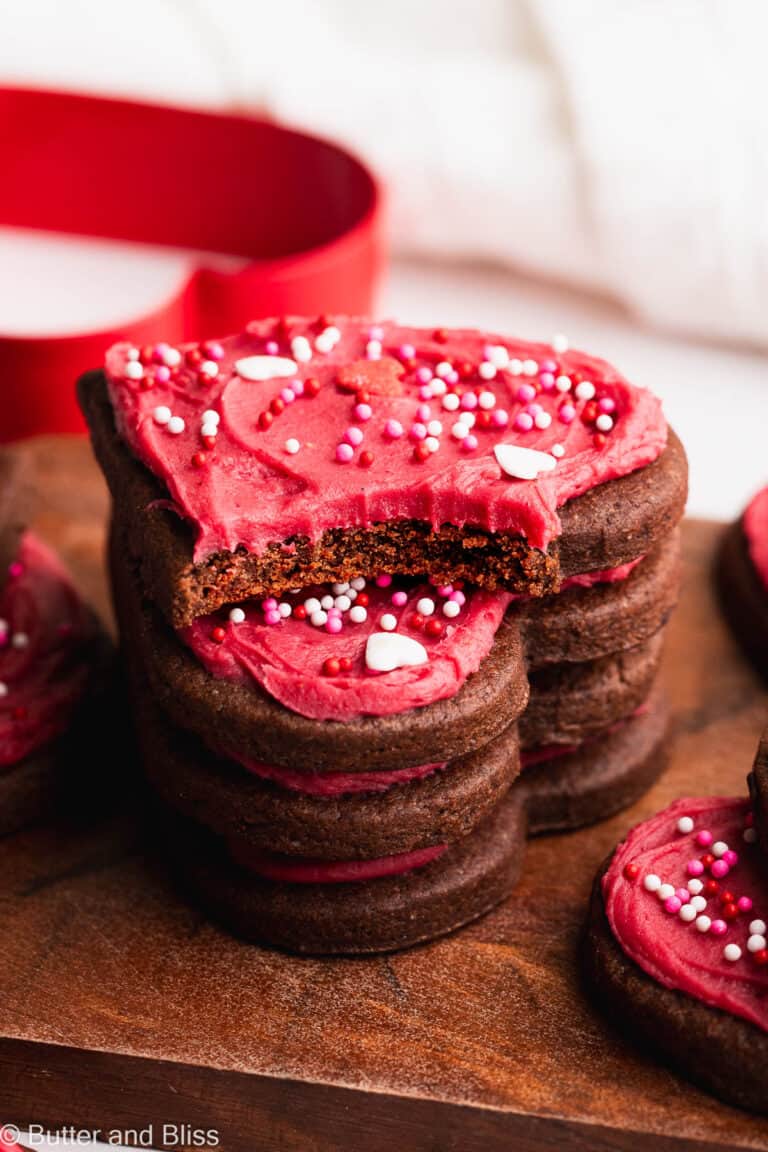 Chocolate heart shaped cookies in a stack with a tasty bite out of the top one.