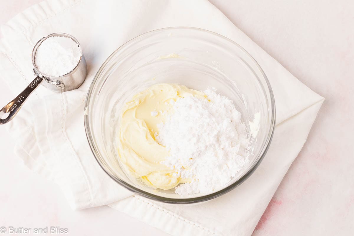 Powdered sugar sprinkled over whipped butter mix in a bowl.