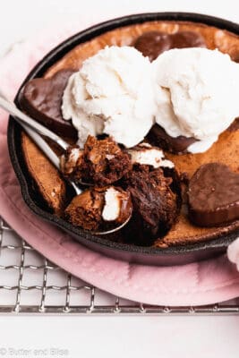 Super fudgy brownie skillet being eaten with two spoons and topped with ice cream.