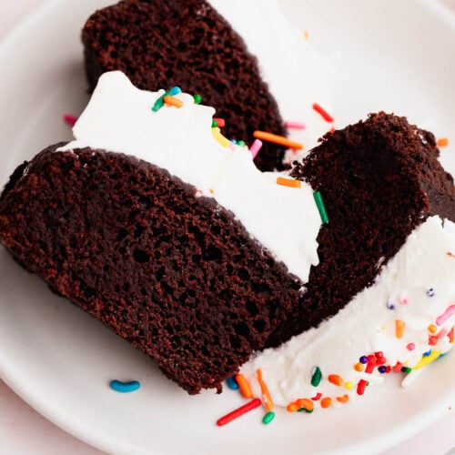 Slices of chocoalte wacky cake with whipped cream frosting on a white plate.