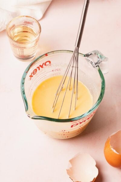 Liquid cake ingredients mixed in a glass measuring cup.
