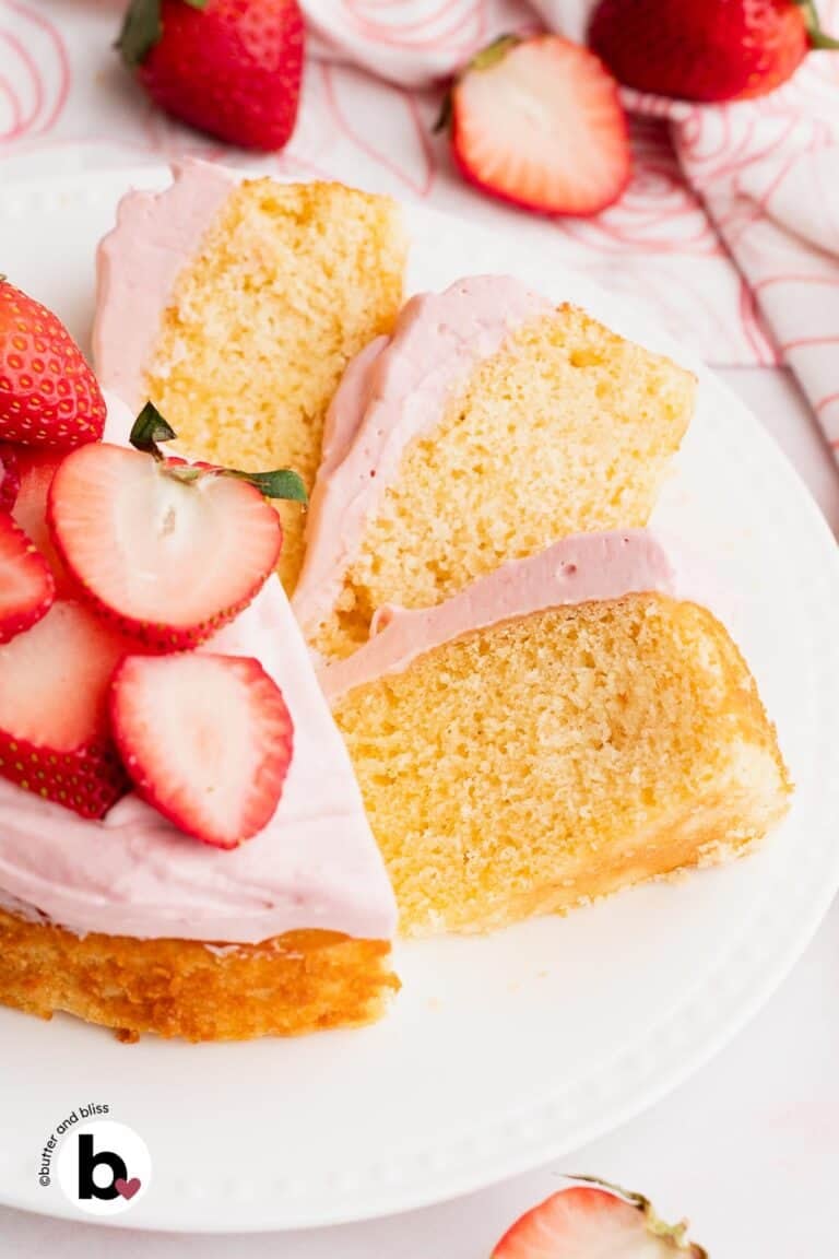 Pretty slices of a small vanilla cake topped with strawberry frosting fanned out on a plate.