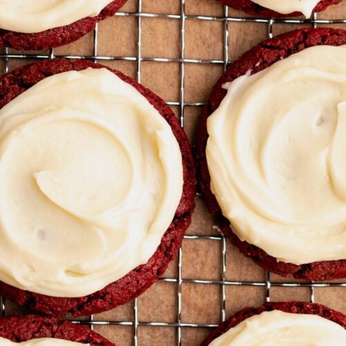 Cookie frosting spread on a batch of red cookies.
