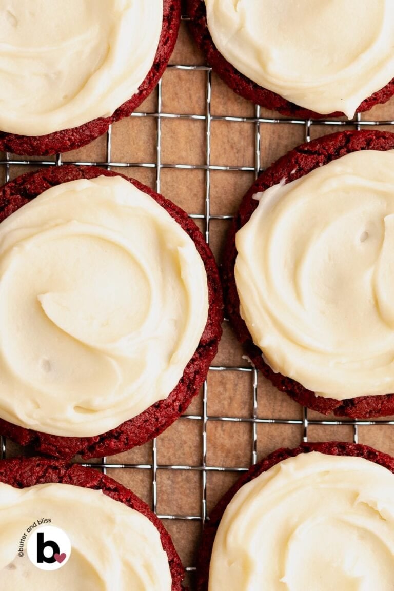 Cookie frosting spread on a batch of red cookies.