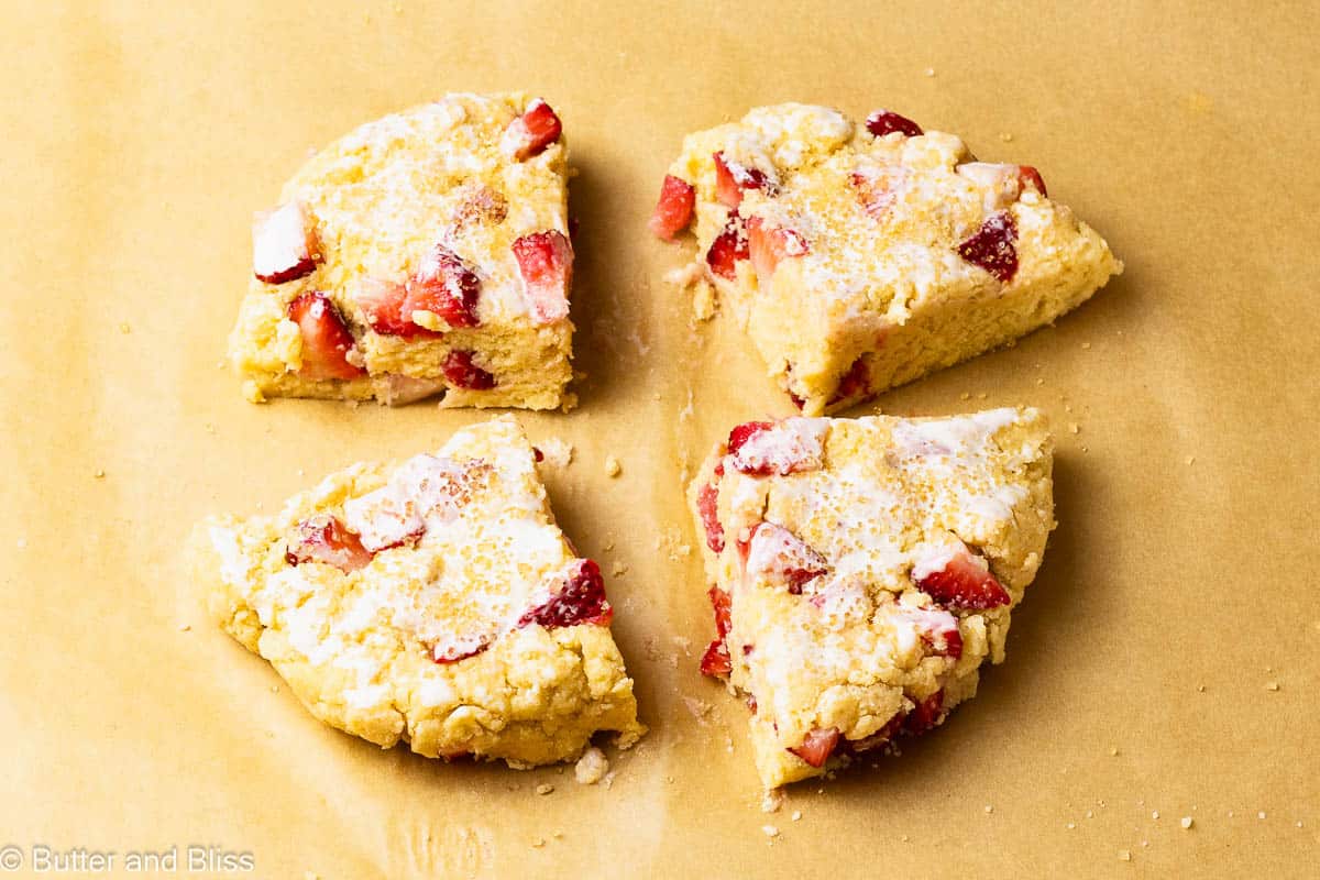 Raw strawberry scones cut into wedges on a baking sheet.