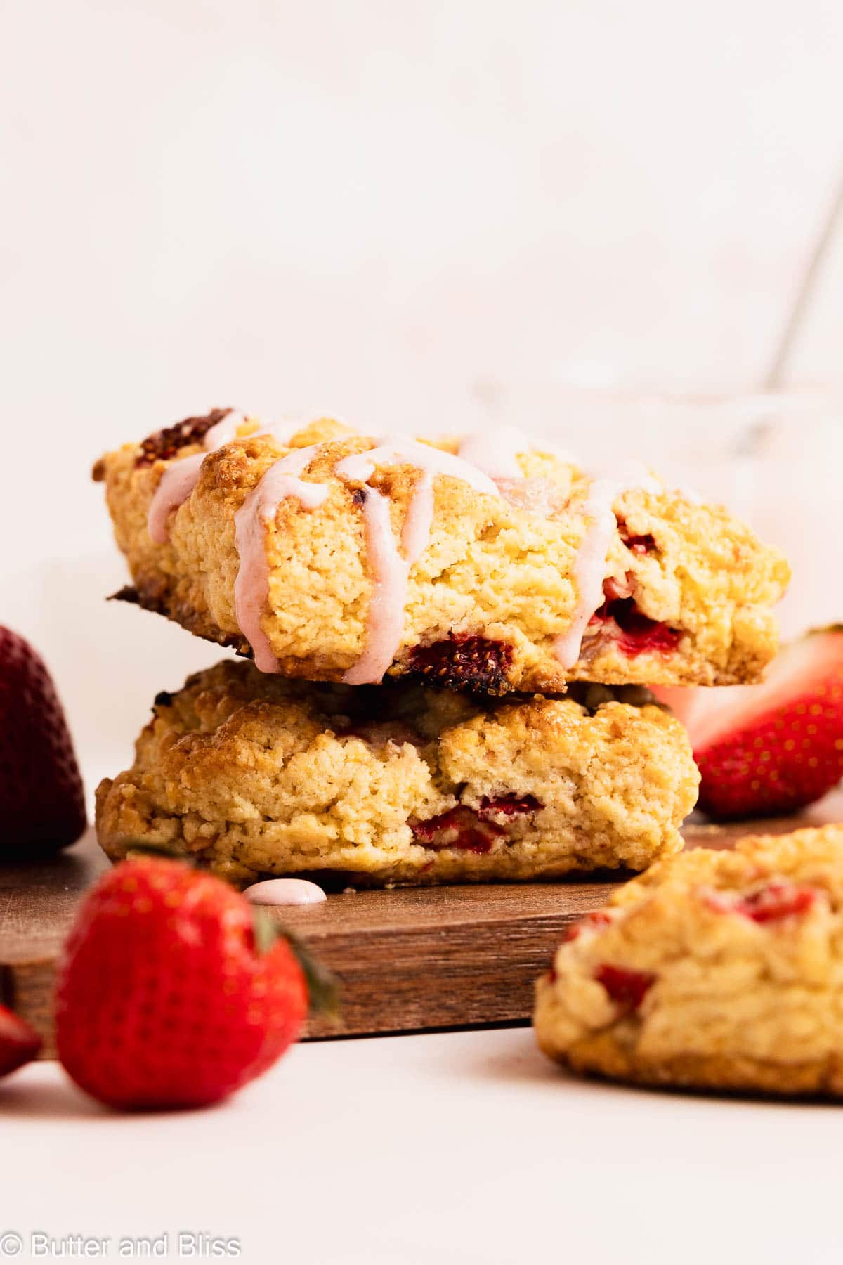 A pretty stack of two fresh strawberry breakfast scones with creamy strawberry glaze on top.