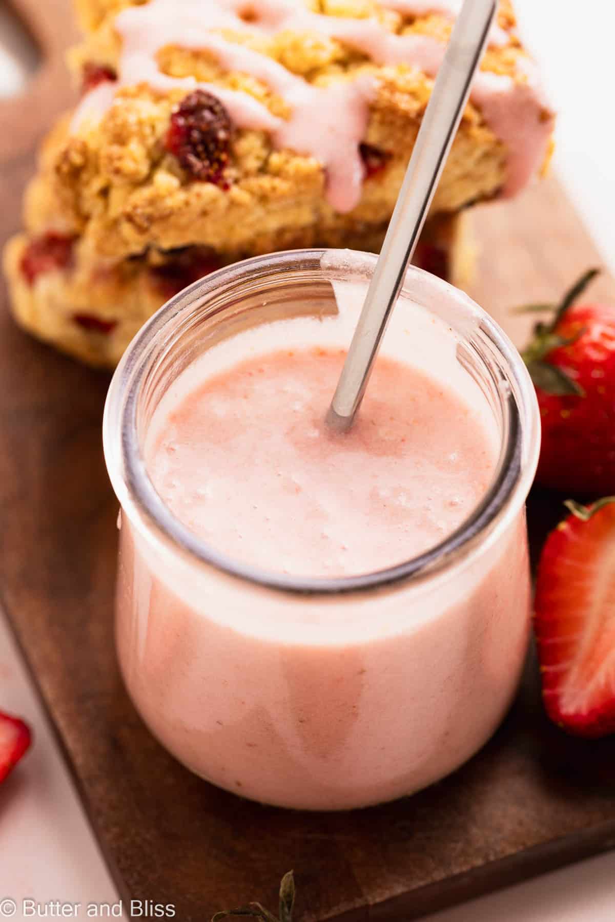 Fresh strawberry glaze in a small glass jar surrounded by pastries.