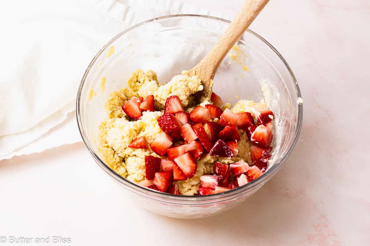 Chopped strawberries added to a bowl of scone dough.