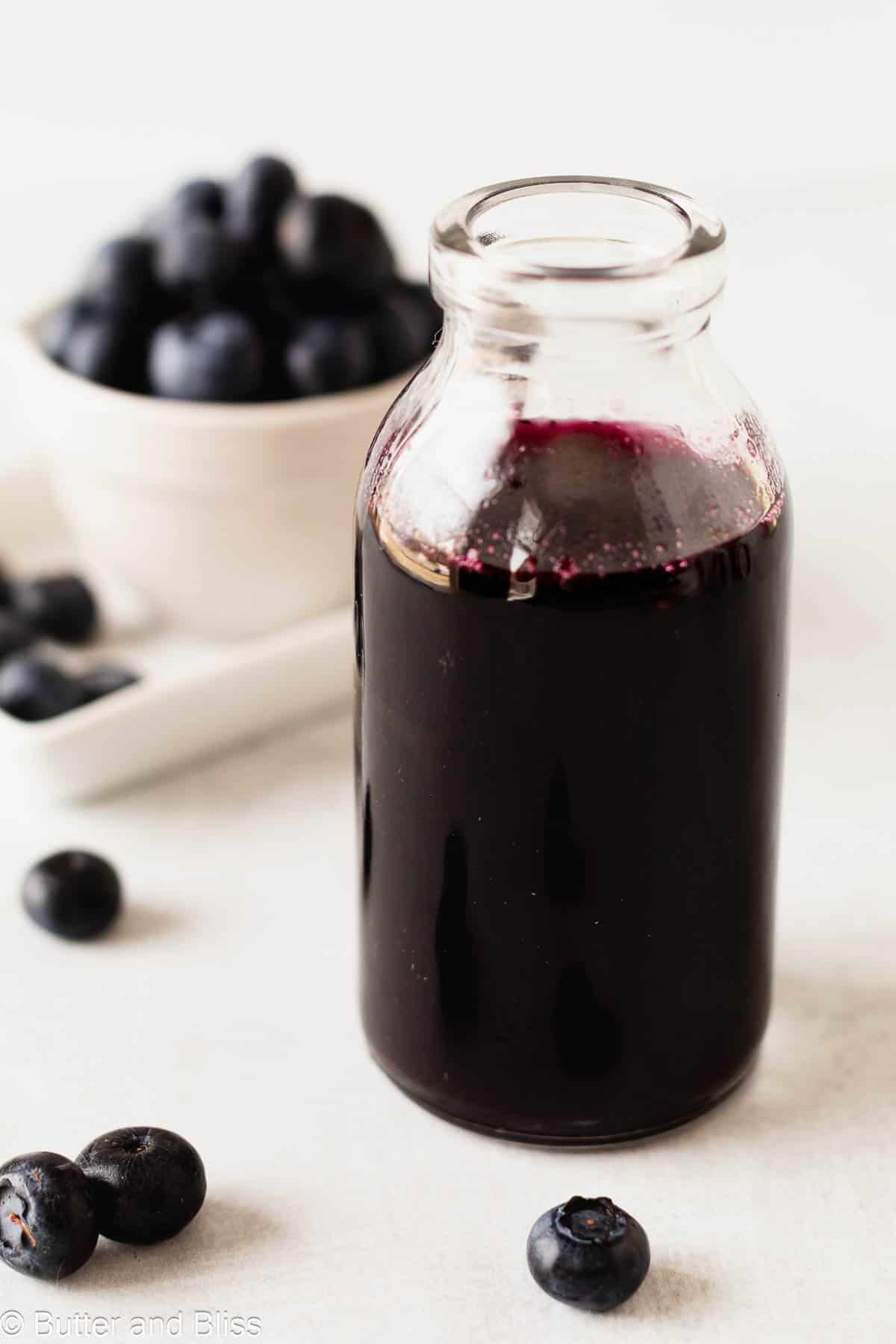 Homemade blueberry lemonade syrup in a small glass jar.