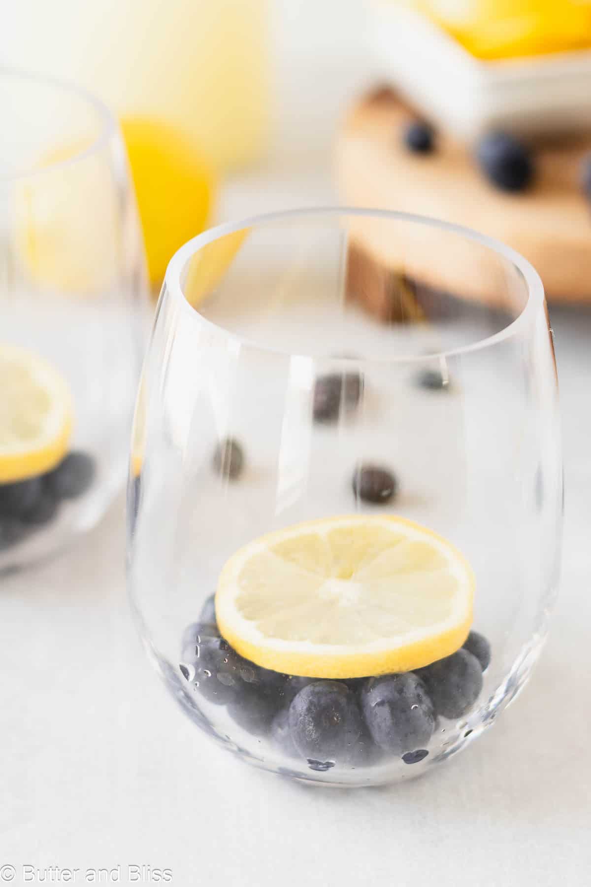 Fresh summer berries in a glass topped with a slice of bright lemon.