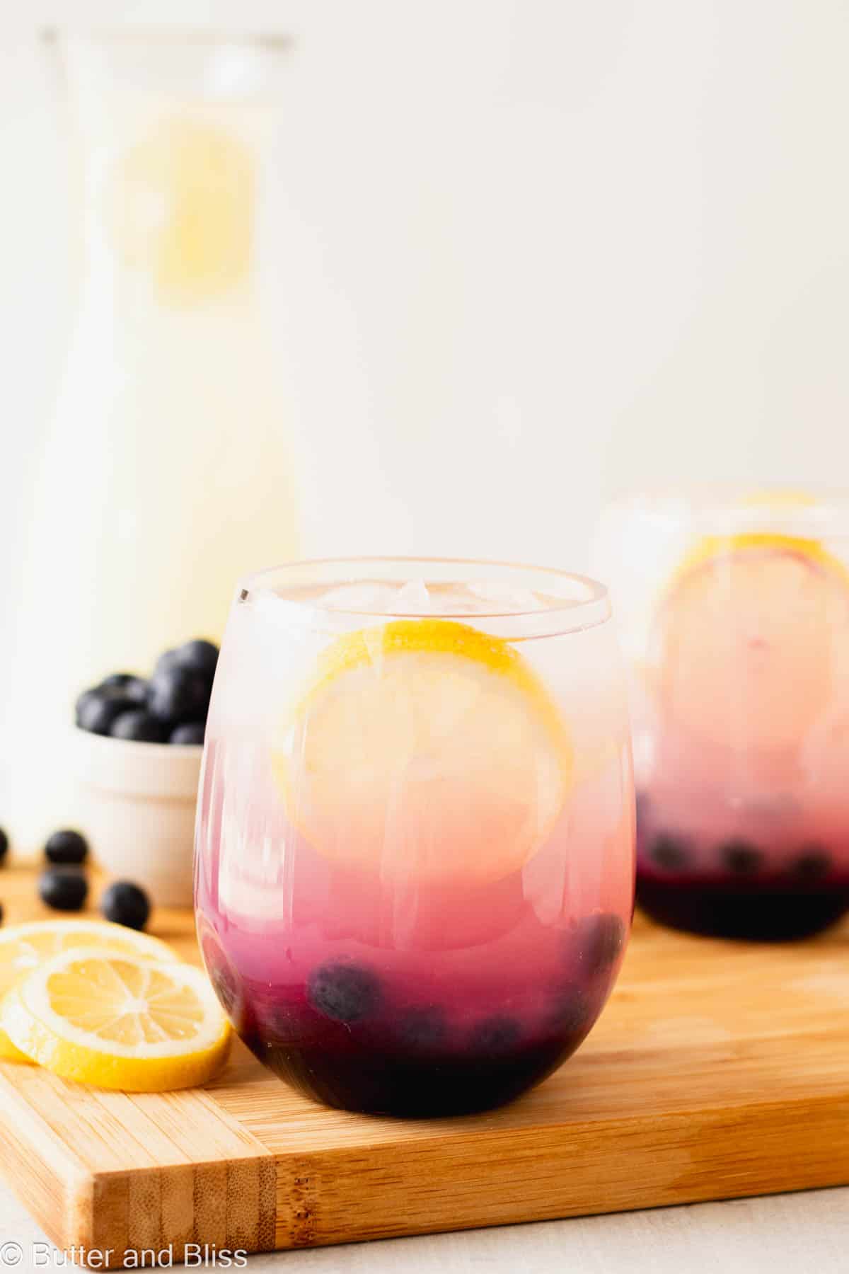 Blueberry lemonade in a glass set on a wood serving tray.