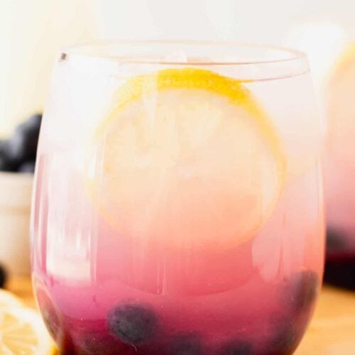 Beautiful close up of blueberry lemonade a glass with a slice of lemon.