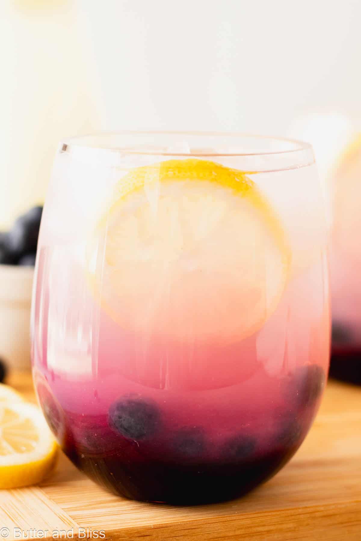 Beautiful close up of blueberry lemonade a glass with a slice of lemon.