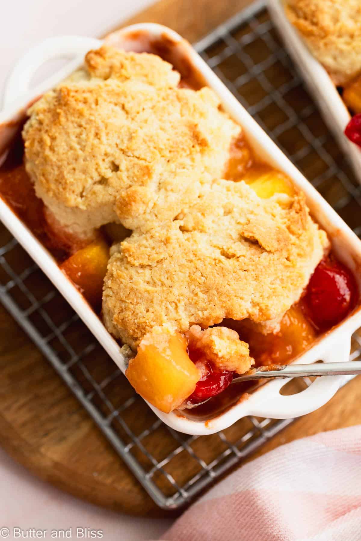 Gooey insides and crunchy biscuit outside of a pineapple upside down cobbler in a white serving dish.