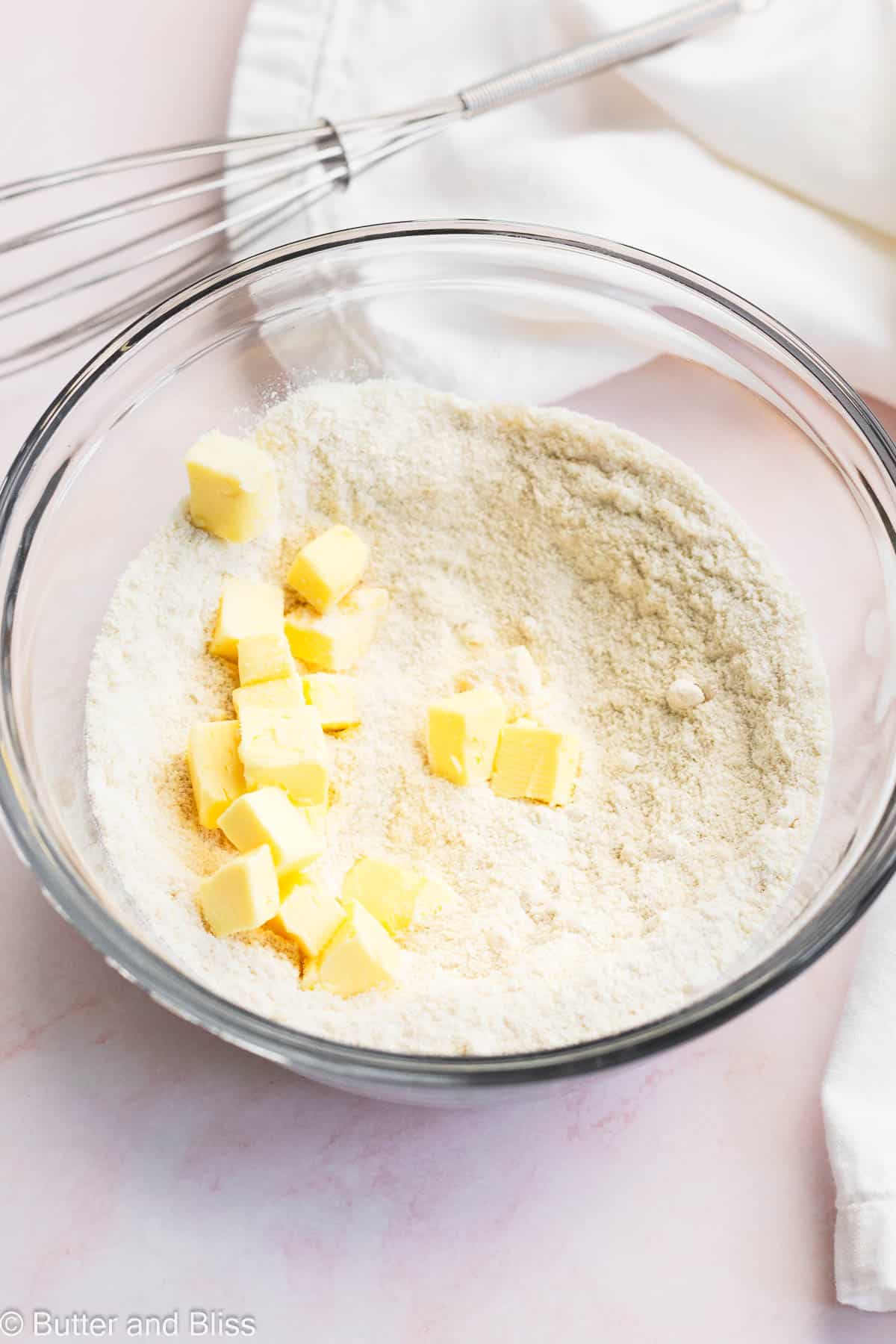 Butter tossed on dry ingredients in a mixing bowl.
