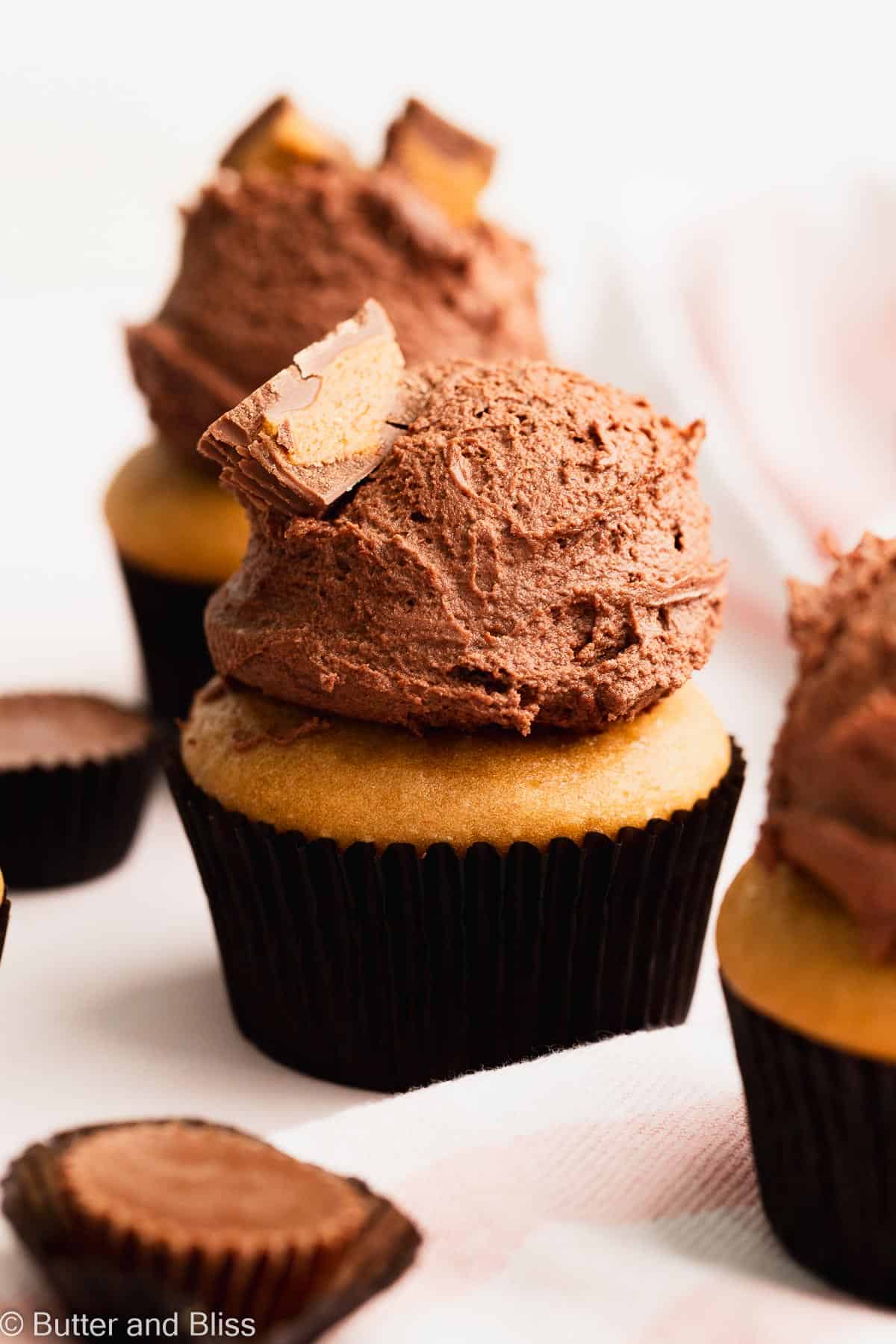 Large scoop of peanut butter chocolate frosting on a cupcake and topped with peanut butter cup candy.