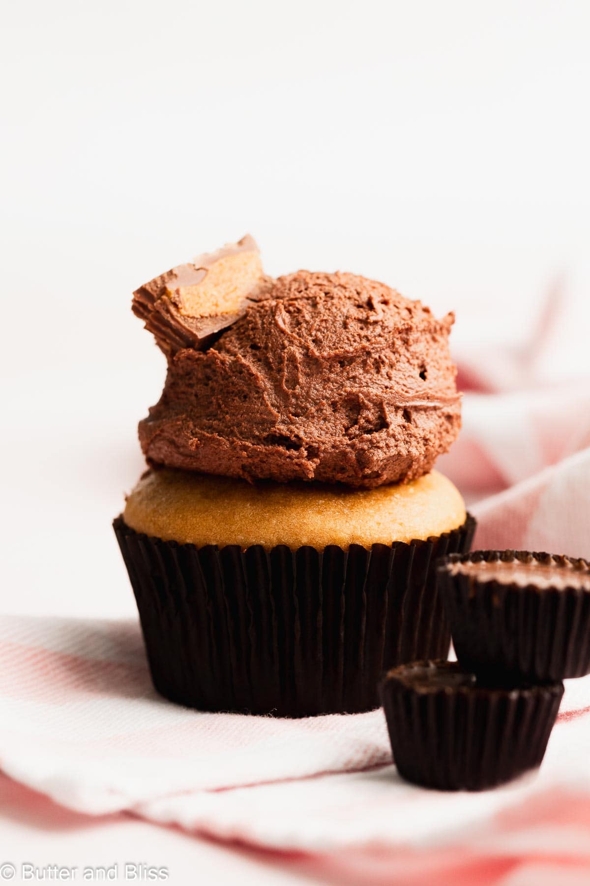 Pretty cupcake with large dollop of chocolate peanut butter frosting on top.