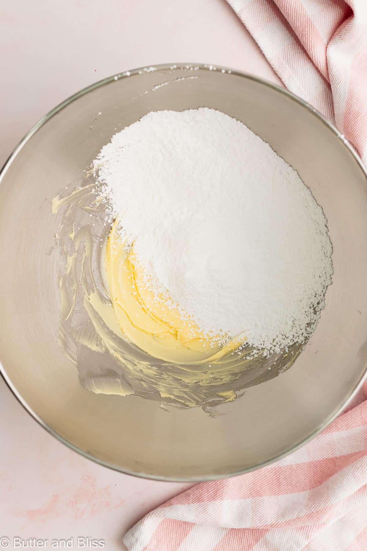 Powdered sugar added to creamed butter in a mixing bowl.