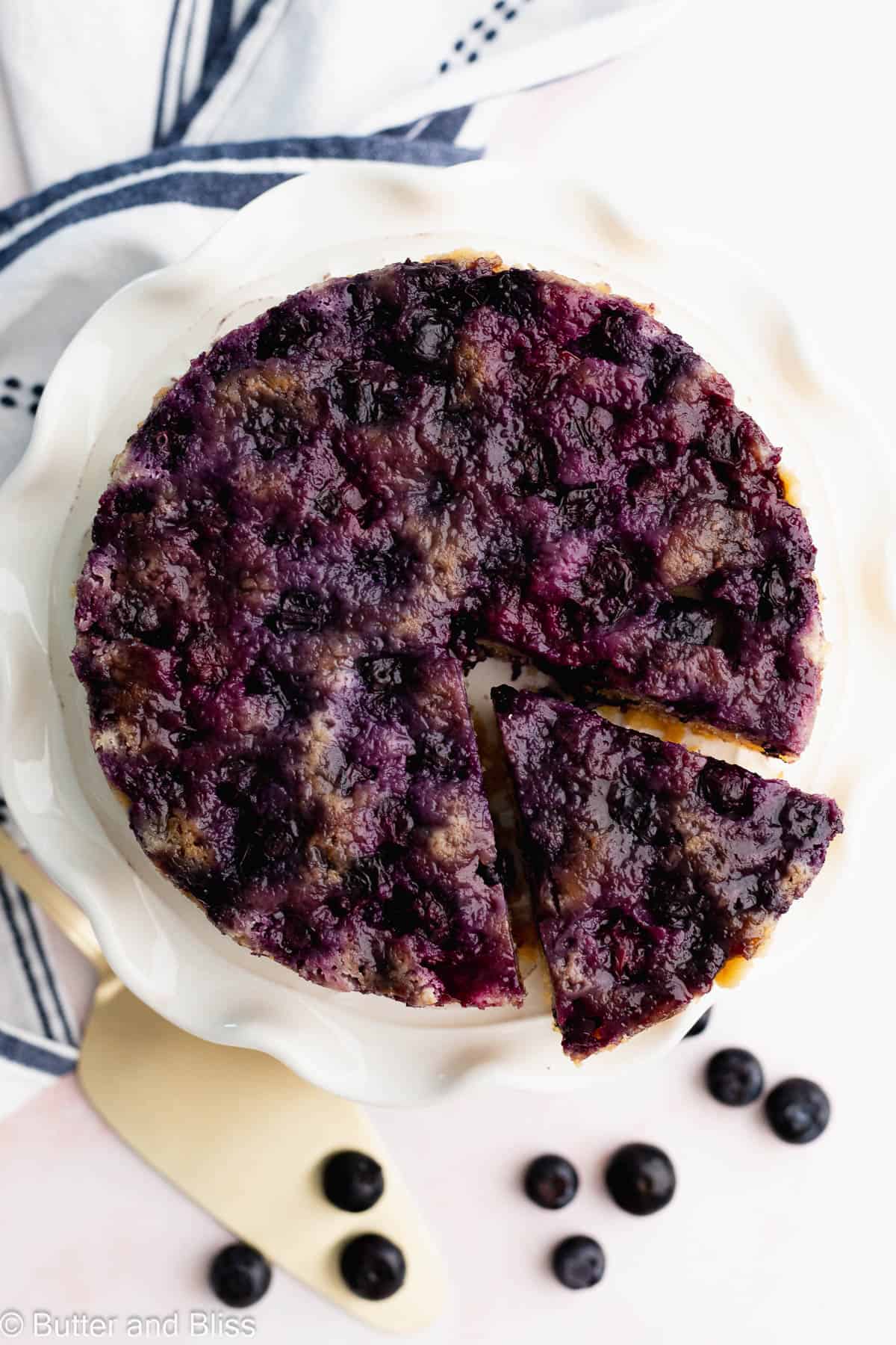 Top of a blueberry upside down cake on a cake platter with tons of jammy blueberries.