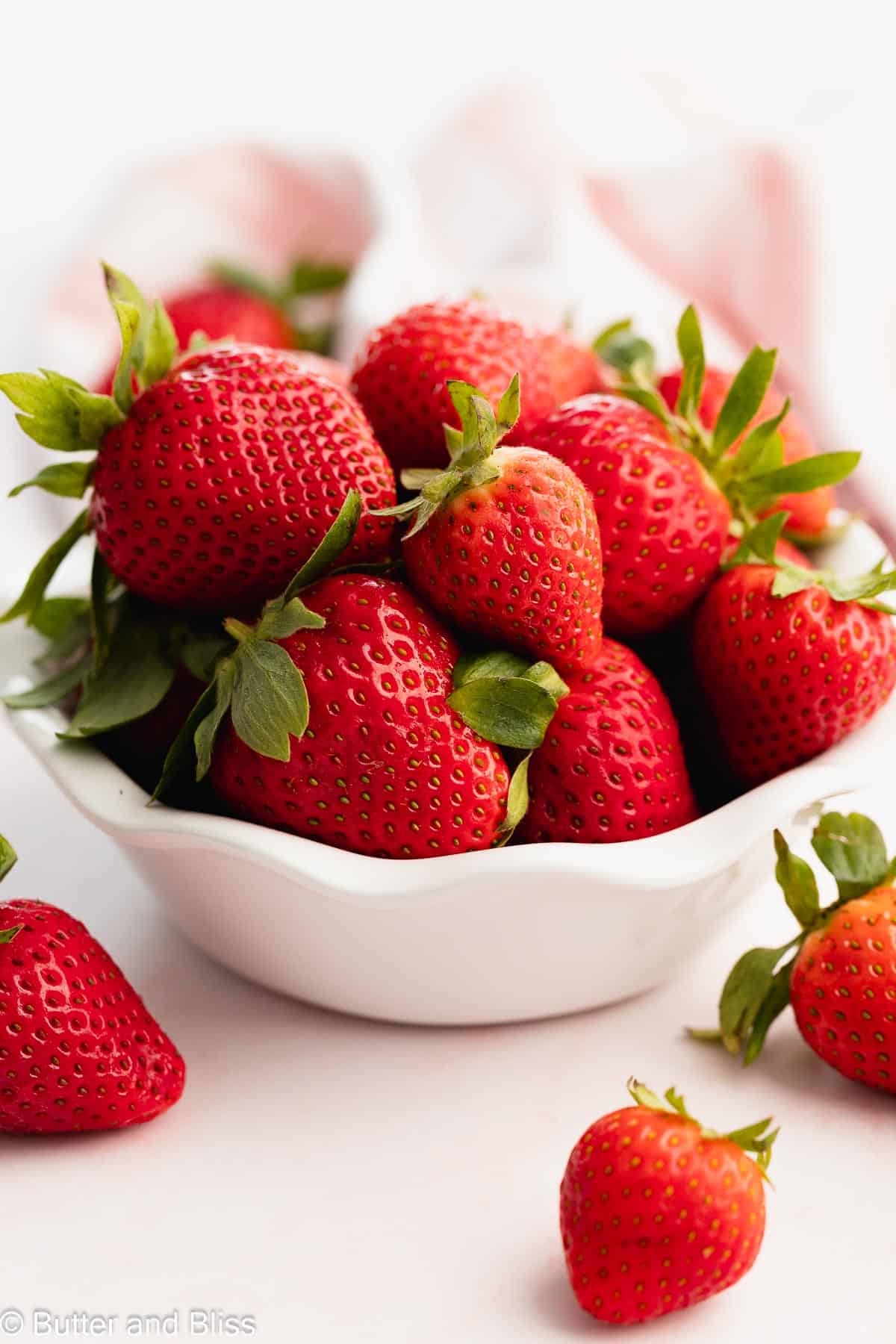 A pretty white bowl full of fresh strawberries.
