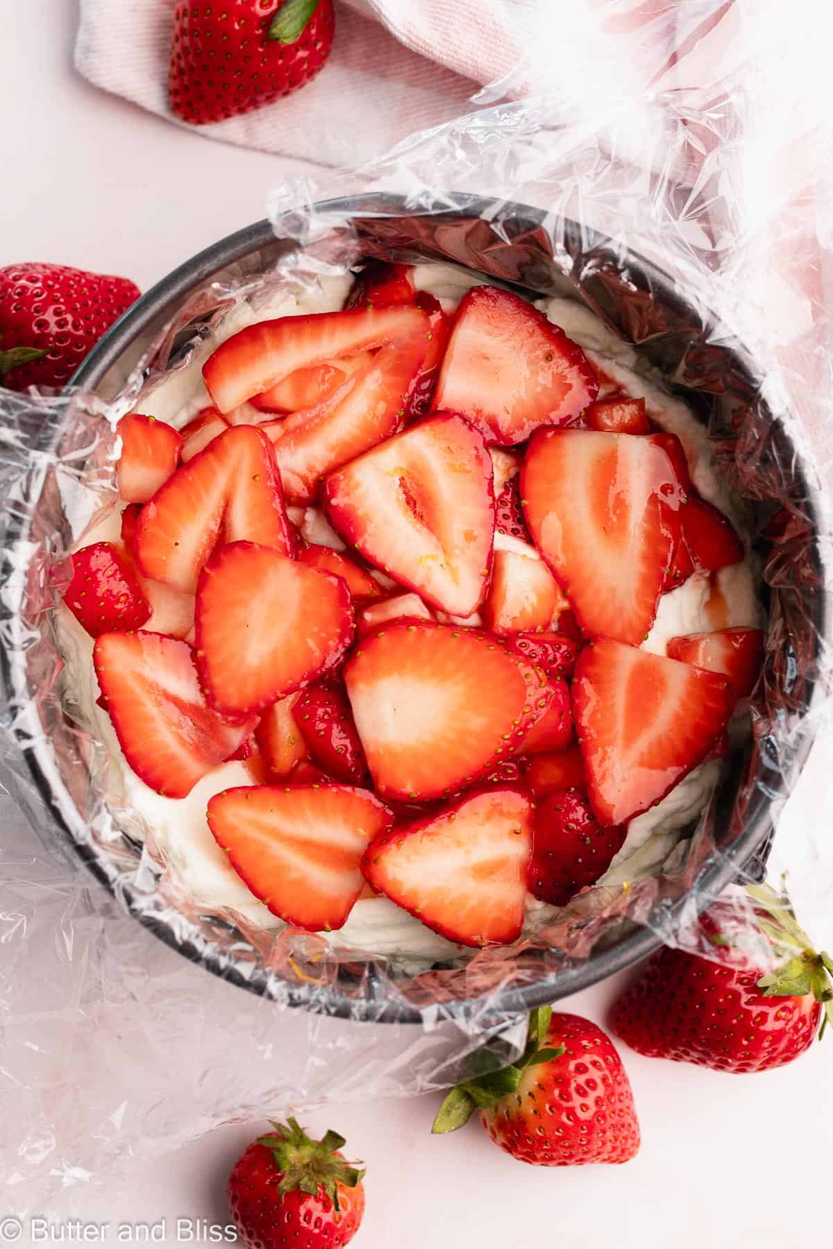 A small strawberry icebox cake being assembled in a springform pan.