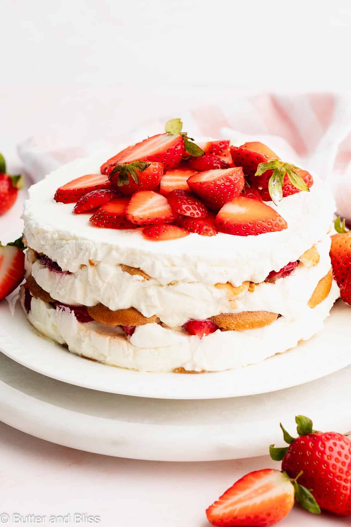 Pretty side view of all the layers in a small strawberry icebox cake on a white platter.