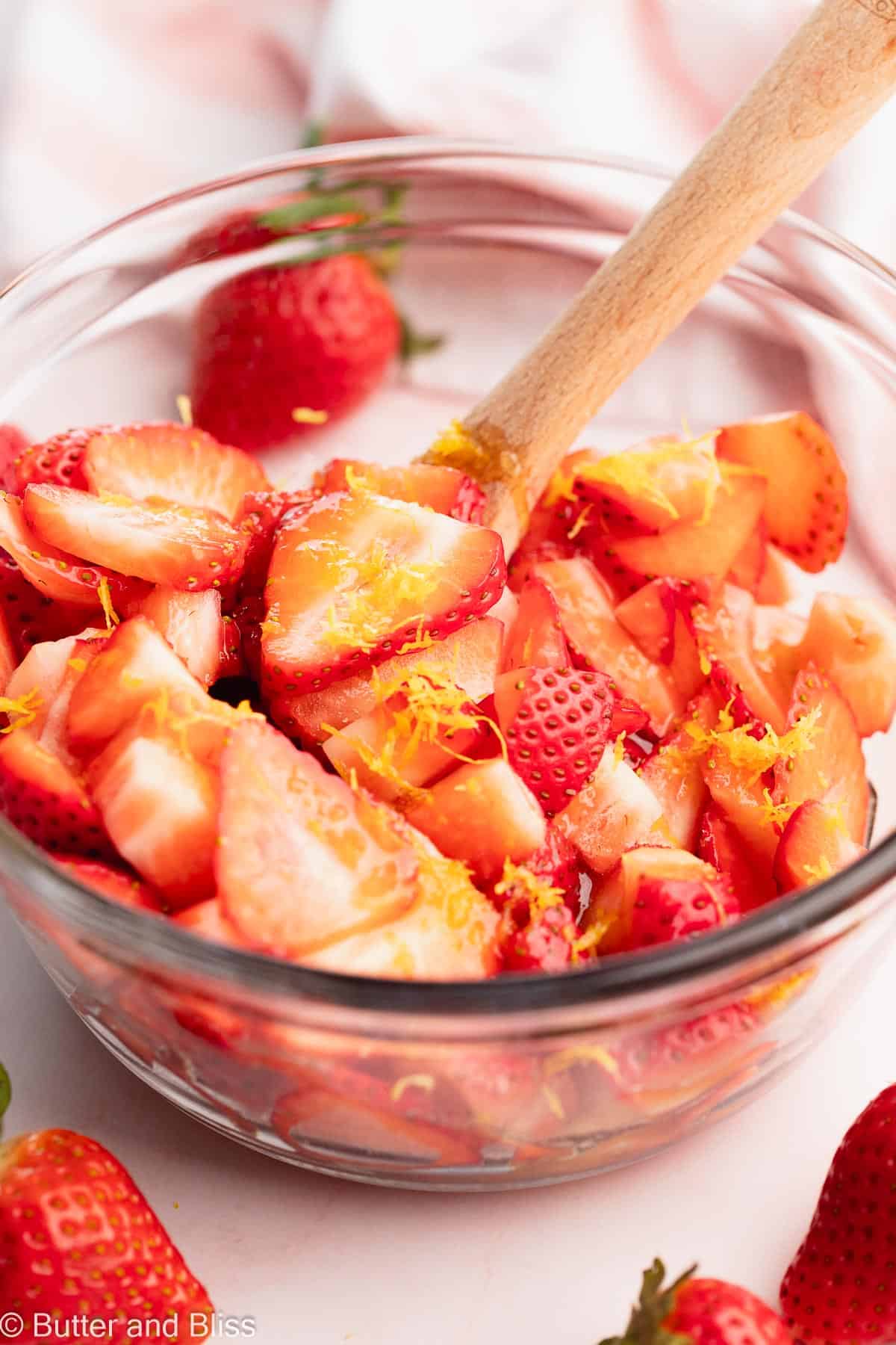A mixing bowl of fresh strawberries and lemon zest.