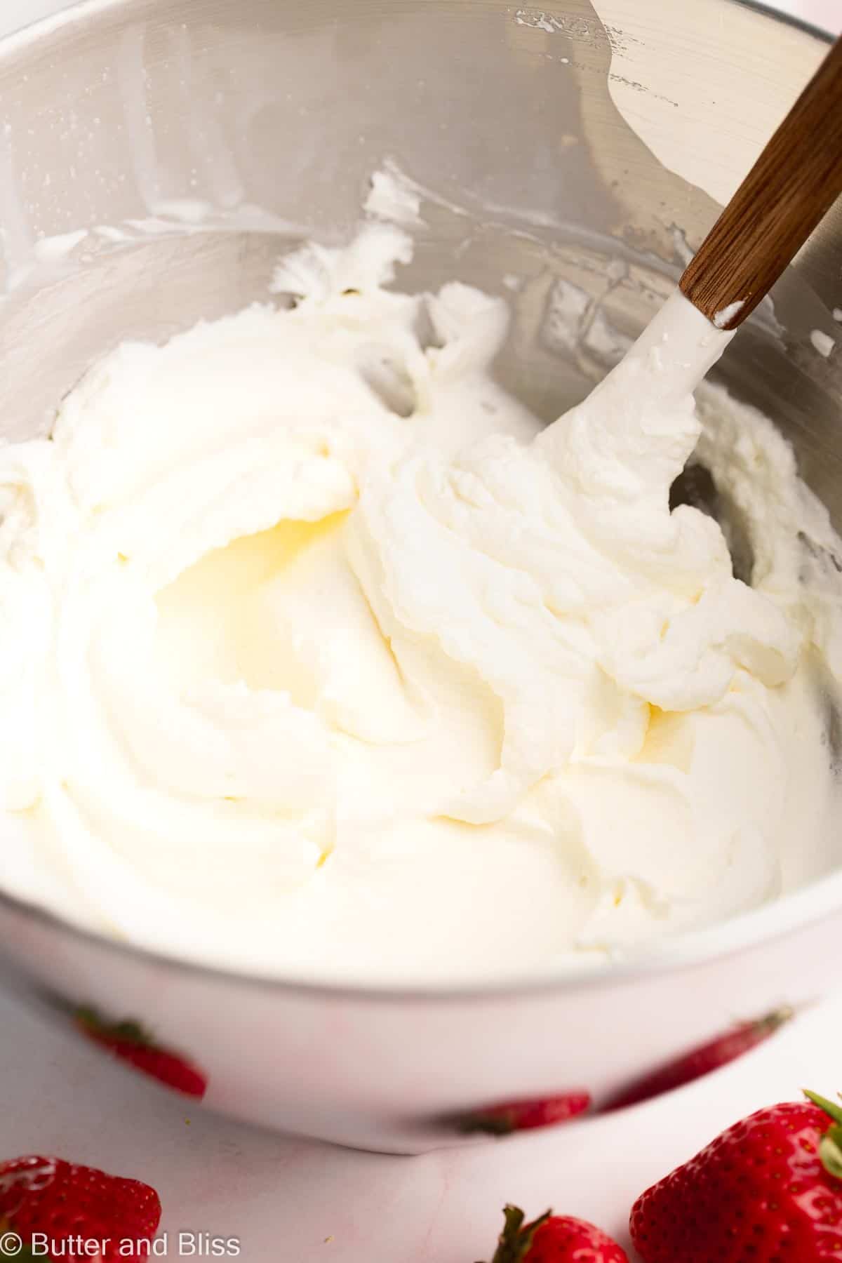 A mixing bowl full of fluffy whipped cream.