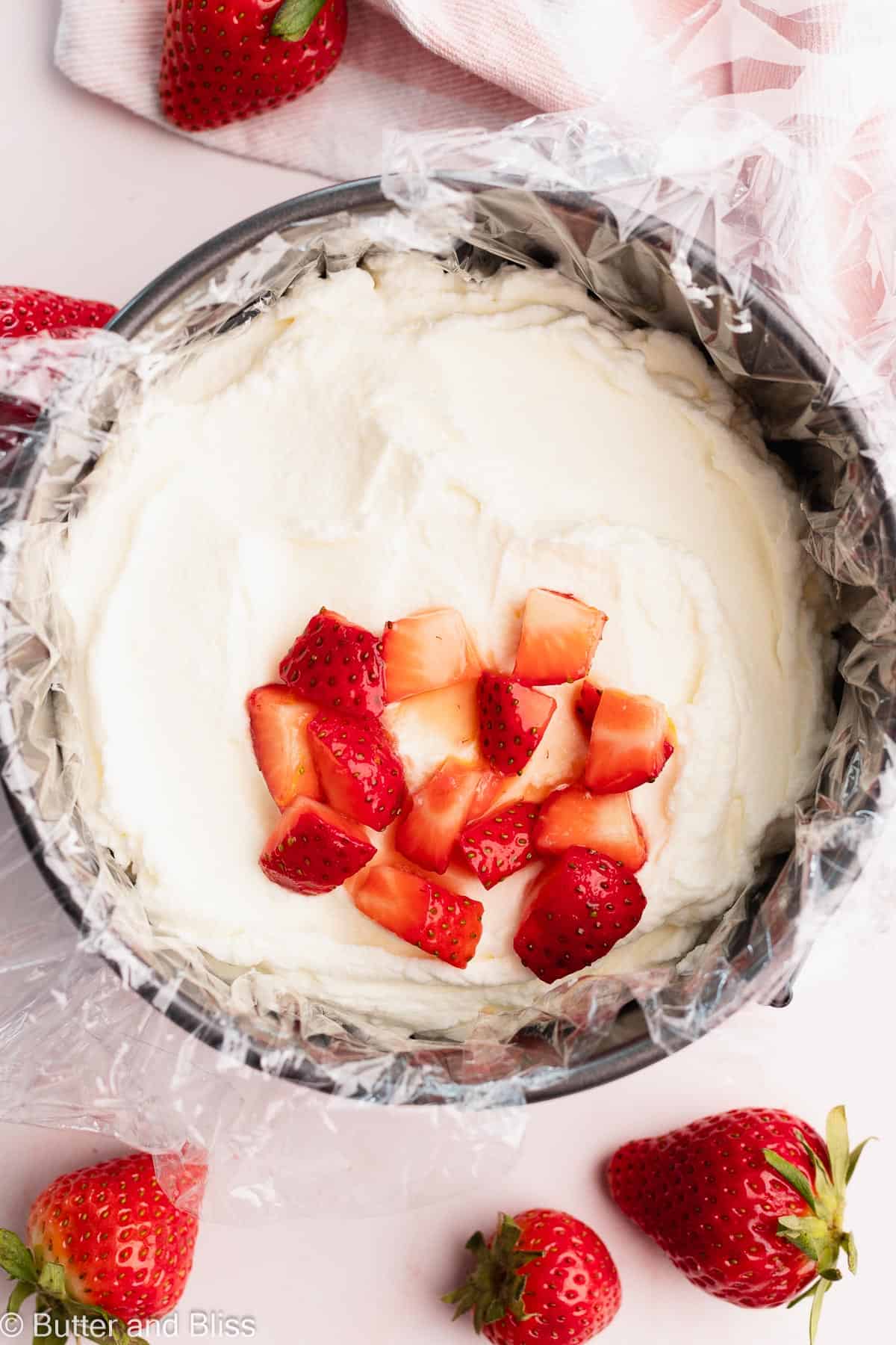 Small springform pan filled with whipped cream and a layer of chopped strawberries.
