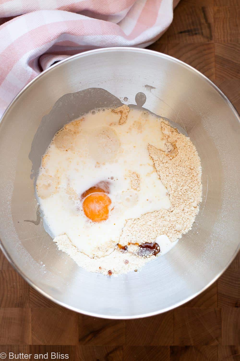 Wet cupcake ingredients added to dry ingredients in a mixing bowl.