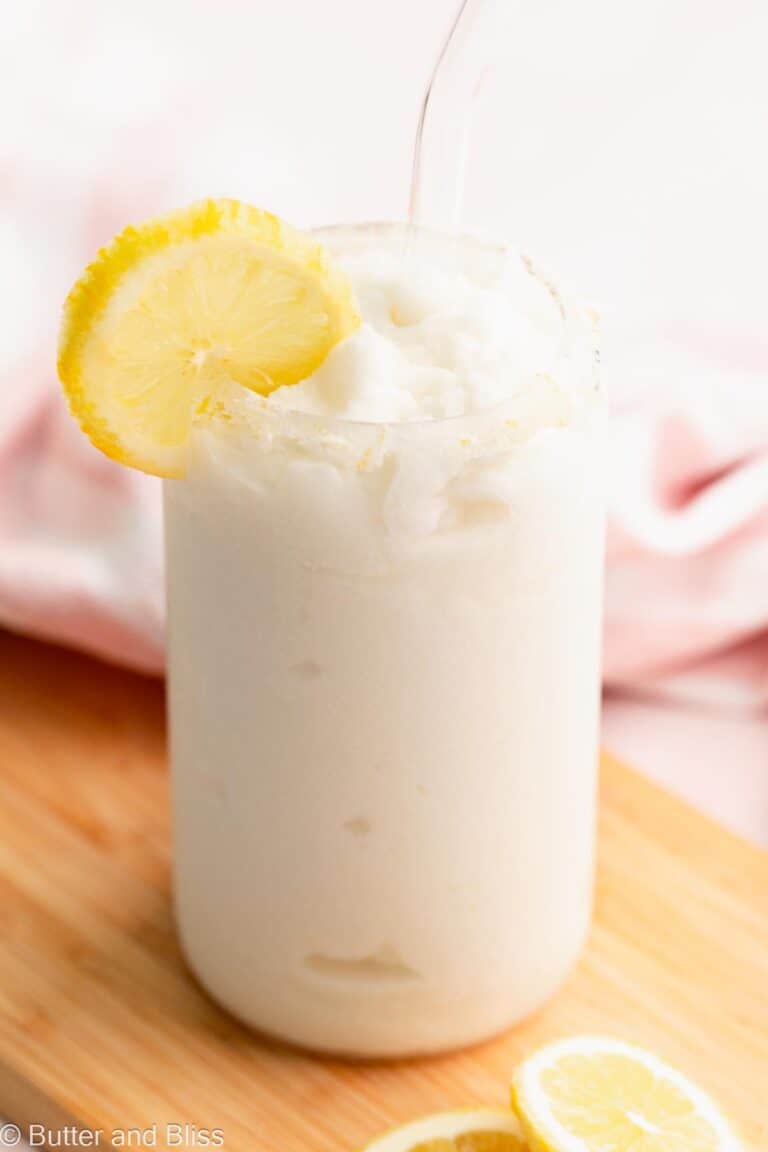 Creamy whipped frozen lemonade in a pretty glass with a sugar rim and lemon slice.