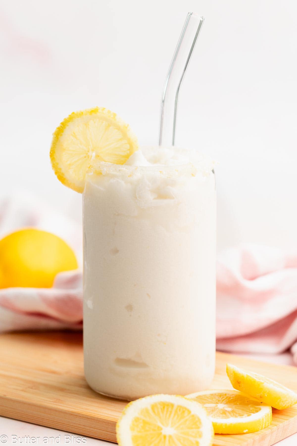 A glass of creamy frozen lemonade garnished with a lemon slice.